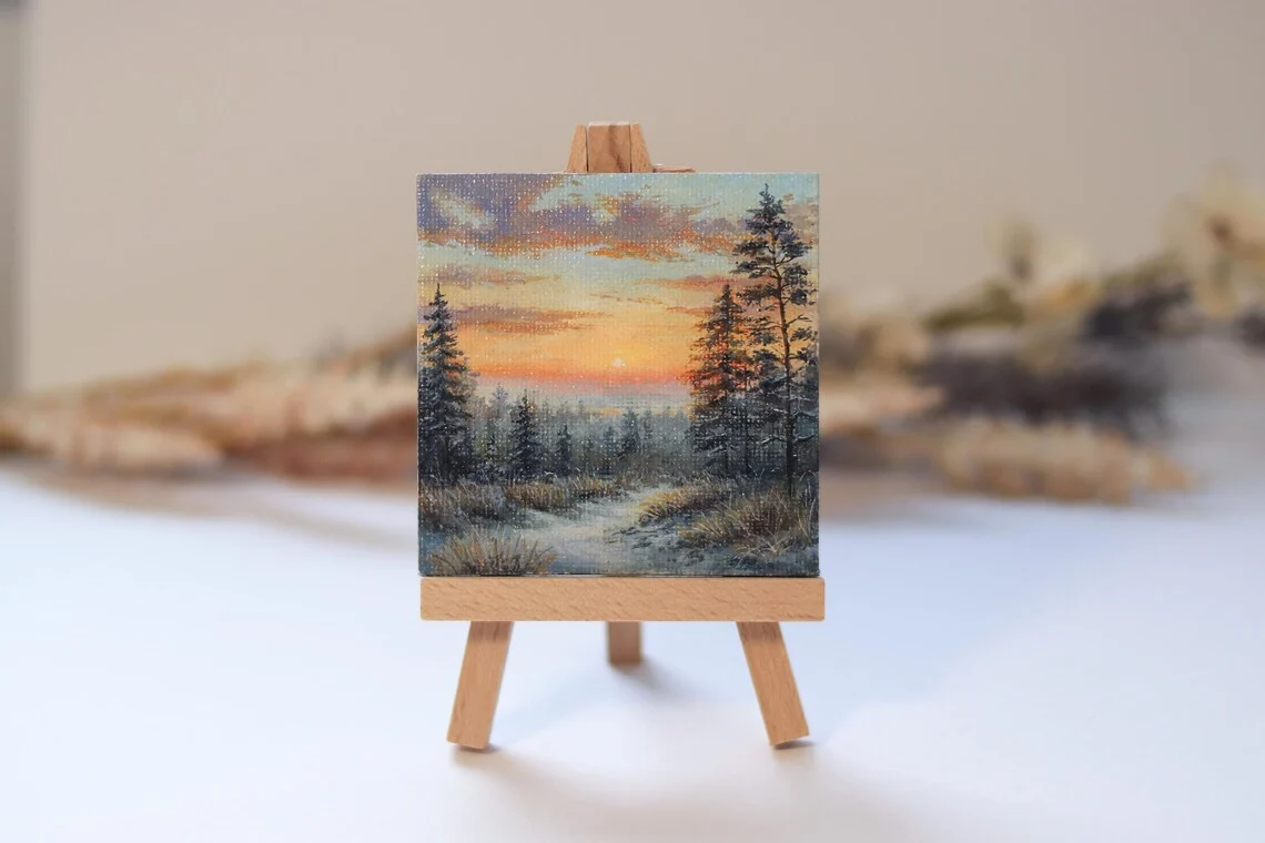 A delicate hand-painted acrylic miniature capturing a peaceful winter sunset over a quiet forest path