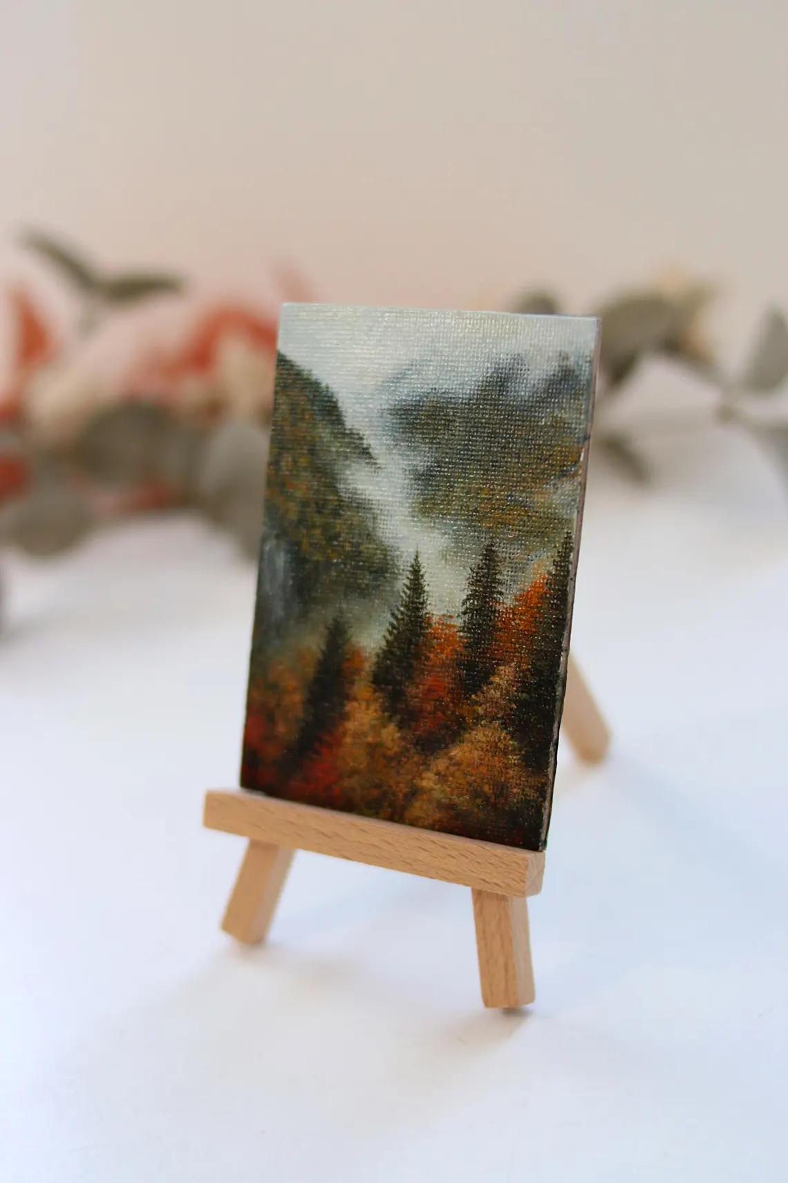 Deep evergreen trees and warm seasonal foliage in miniature autumn mountain acrylic landscape painting